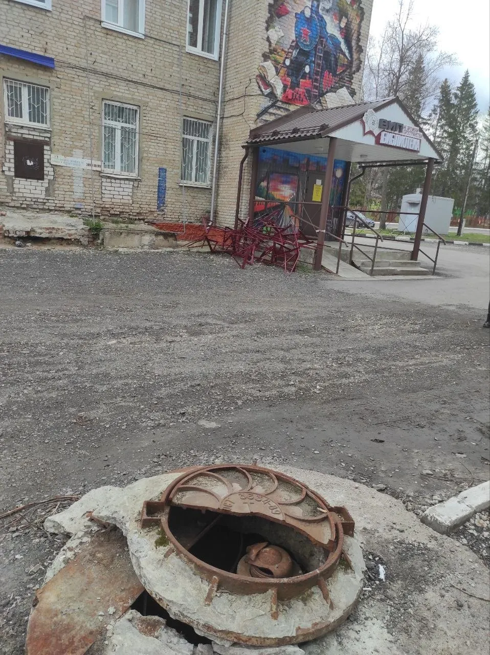 Фото показывает обшитое сайдингом здание детской библиотеки в Шумерле, где со двора видны обвалившиеся элементы и признаки некачественного ремонта; местные проблемы коммунального характера сочетаются с низкими рейтингами властей.